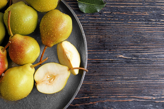 Metal plate with delicious ripe pears on  wooden background