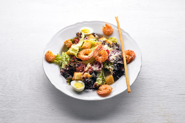 Salad of vegetables and shrimp and quail eggs. On a wooden background. Top view. Free space.