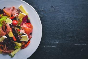 Vegetable salad and diced meat. On a wooden background. Top view. Free space.