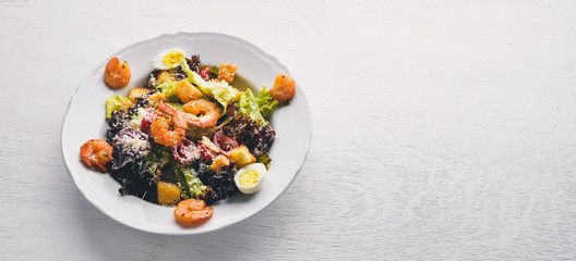 Salad of vegetables and shrimp and quail eggs. On a wooden background. Top view. Free space.