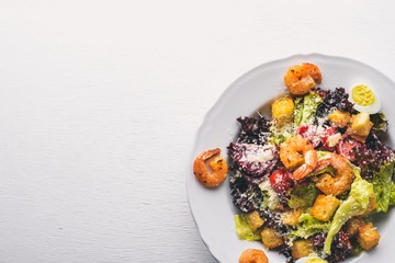 Salad of vegetables and shrimp and quail eggs. On a wooden background. Top view. Free space.