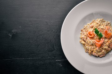 Risotto with salmon and cream sauce. On a wooden background. Top view. Free space.