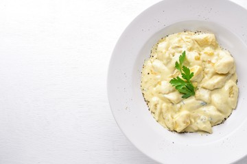 Dumpling from potatoes under cheese sauce. On a wooden background. Top view. Free space.