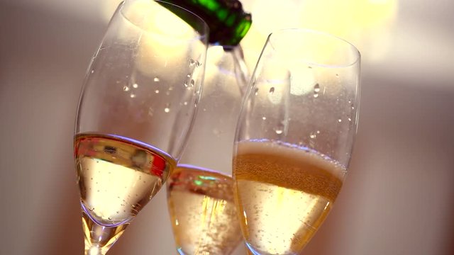 Champagne. Glasses with sparkling champagne toasting over holiday golden bokeh blinking background. 4K UHD video 3840X2160