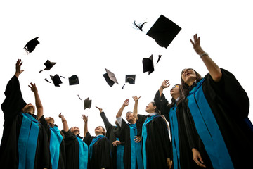 Group of graduates with congratulations throwing graduation hats in the air celebrating with white isolate background. 