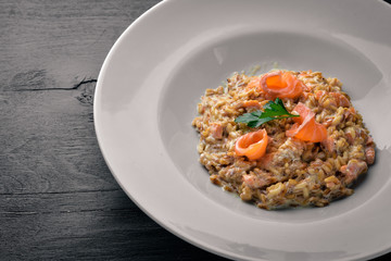 Risotto with salmon and cream sauce. On a wooden background. Top view. Free space.