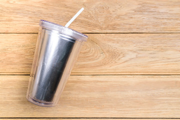 Top view plastic tumbler cup with straw or tube on wooden background