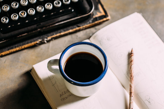Enamel cup with coffee and retro typewriter