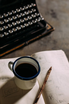 Enamel cup with coffee and retro typewriter