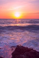 Fototapeta na wymiar the wave breaks against the stone against the setting sun.