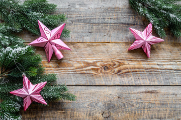 Christmas toys. Pink stars near pine branches on wooden background top view copyspace