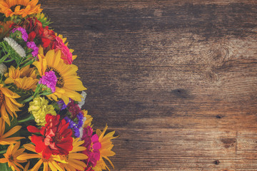 Bright bouquet with fresh fall flowers on wooden textured table with copy space, retro toned