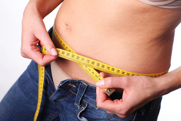 Young woman is measuring her waist. Too many calories. Pregnancy.