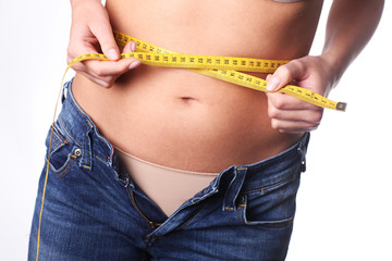 Young woman is measuring her waist. Too many calories. Pregnancy.