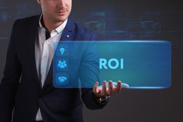Business, Technology, Internet and network concept. Young businessman working on a virtual screen of the future and sees the inscription: ROI