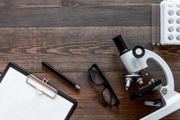 Microscope, pills and tablet on wooden background top view copyspace