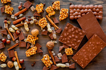 Preparing chocolate. Chocolate bars, nuts, cinnamon on dark wooden background top view