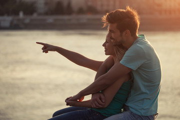 Young couple embracing while watching the sunset over the city.