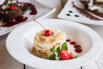 Presentation of delicious desserts in restaurant. napoleon and chocolate cake serving on wooden table, close up picture