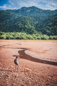 Hiker with a dog on dried lake bed