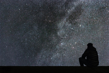 Milky Way. Night sky with stars and silhouette alone man looking at starry sky.