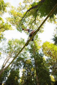 Man walking along a tightrope highline between the trees