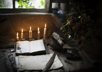 Background with an old book and paper on the table with candles