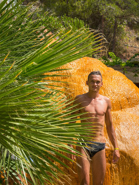A young man is stands near a hot mineral spring. Turkey. Karahayit (near the city of Denizli) - red-brown-orange travertine with mineral water