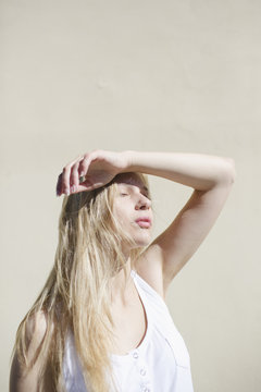 Blonde girl with arm raised for sun protection