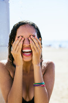 Smiling woman taking a shower on the beach.