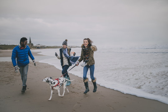 Teenagers Walk Dog On Winter Beach