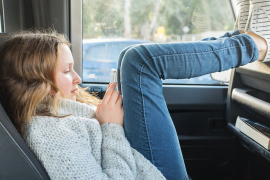 teen girl waiting in the car on her phone