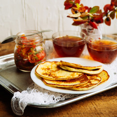 Home-made breakfast or brunch: american style pancakes served with berries and sugar powder on vintage metal tray with a cup of black tea