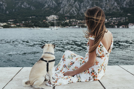 Young woman and her pug dog Max by the sea