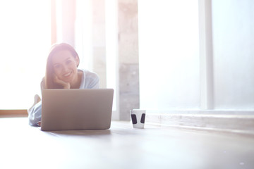 Young beautiful woman at home sitting on the floor with laptop. Young beautiful woman.