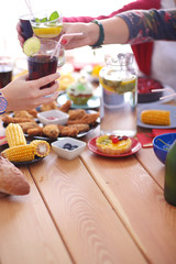 Top view of group of people having dinner together while sitting at wooden table. Food on the table. People eat fast food.