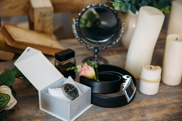 Wedding groom accessories, details of clothes, belt, wristwatch, boutonniere, perfume.