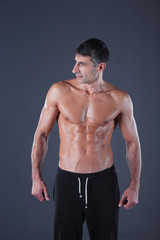 Fototapeta na wymiar muscular man. Muscular man on a grey background showing muscles. Fitness instructor. Fitness professional. Workout. Men's fitness.