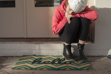 Girl at front door mat hello