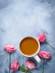 Fototapeta na wymiar Mug of coffee and pink flowers on blue background. Flat lay festive mother valentine day greeting card