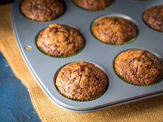 Banana chocolate muffins with caramel sugar topping on dark background