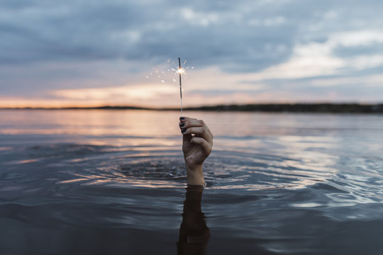 Evening portrait of person underwater holding a sparkler