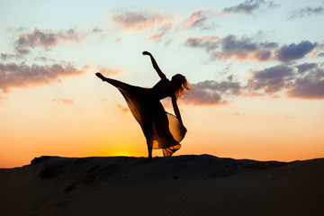 Woman dances at sunrise in the sun. The backlight of the sun only contours of the figures are visible.
