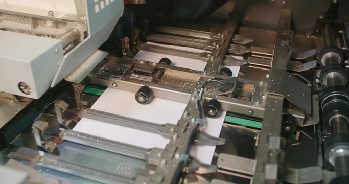 Book Cover Binding Machine Shows Cover Moving Into Place. cover of a paperback book slides into place preparing for binding in an industrial machine
