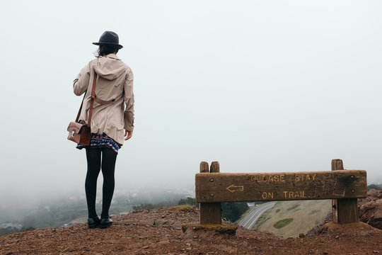 Unrecognizable woman in hat and coat against of foggy San Francisco