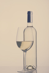 High glass with still white wine and wine bottle, retro toned