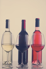 Set of three wine glasses and bottles with red, white and rose wine, retro toned