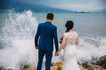 Bride and groom holding hands and turned, back view