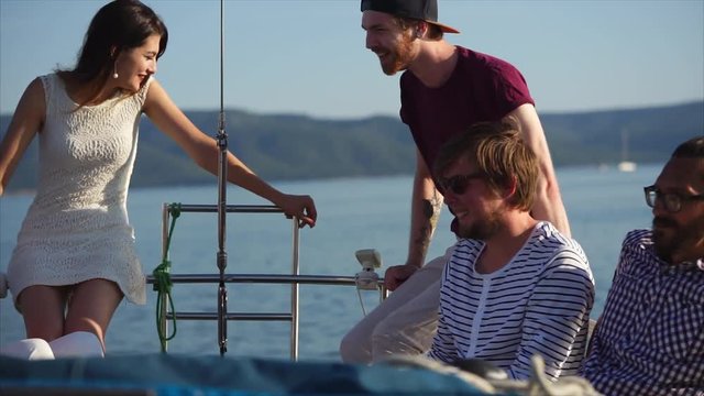 A company of young friends, communicate with each other during the day, buddies are on a yacht in the summer, a nice company of bright people spend their holidays together