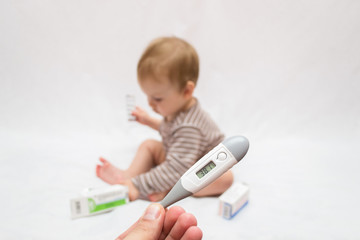 hand holds a thermometer with a high temperature on a white isolated background child with pills